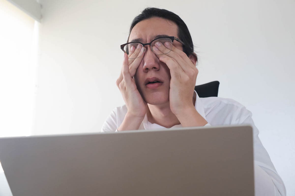 man rubbing eyes due to eye strain