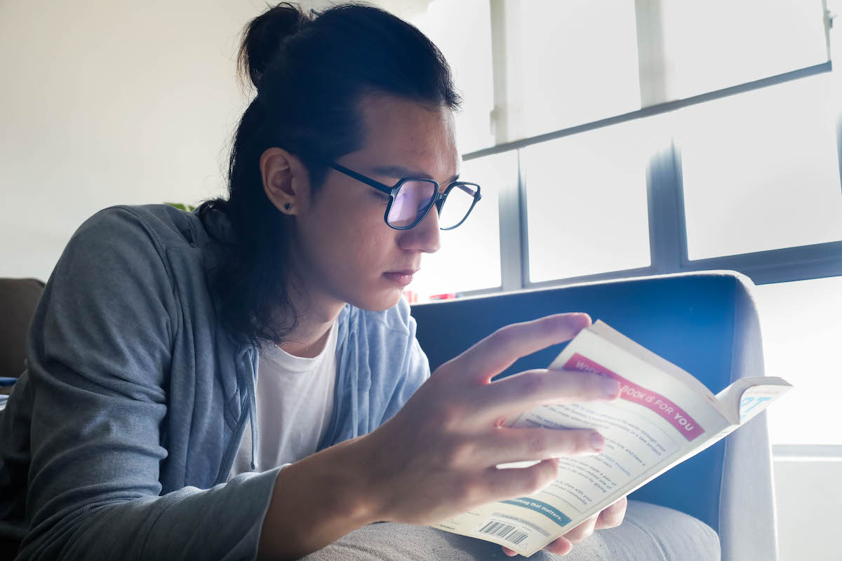 man with reading glasses holding a book