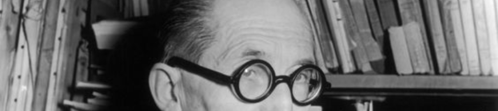 le corbusier wearing his signature round glasses frame
