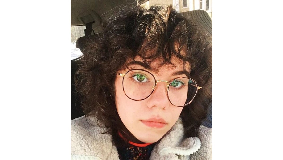 woman with curly bangs wearing round glasses frames