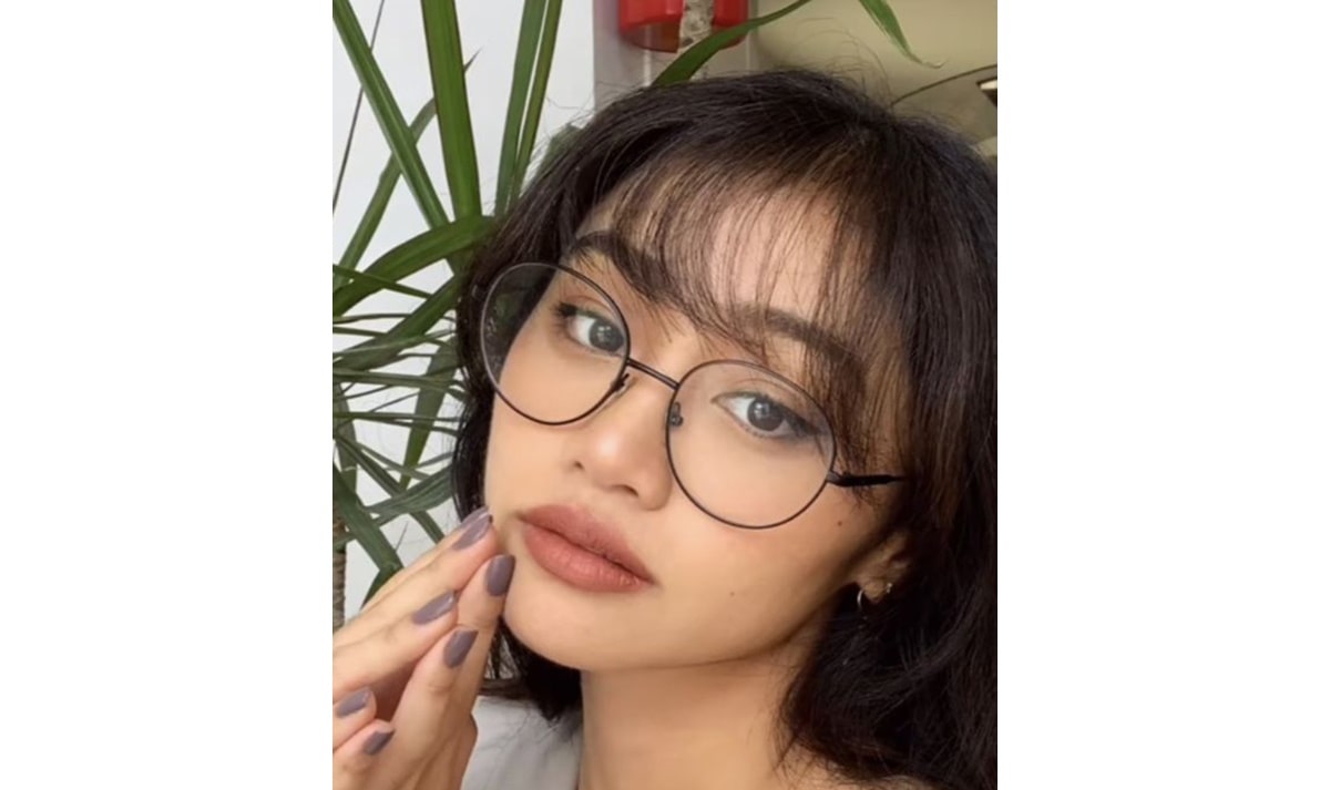 woman with thin wispy bangs wearing metal frame glasses