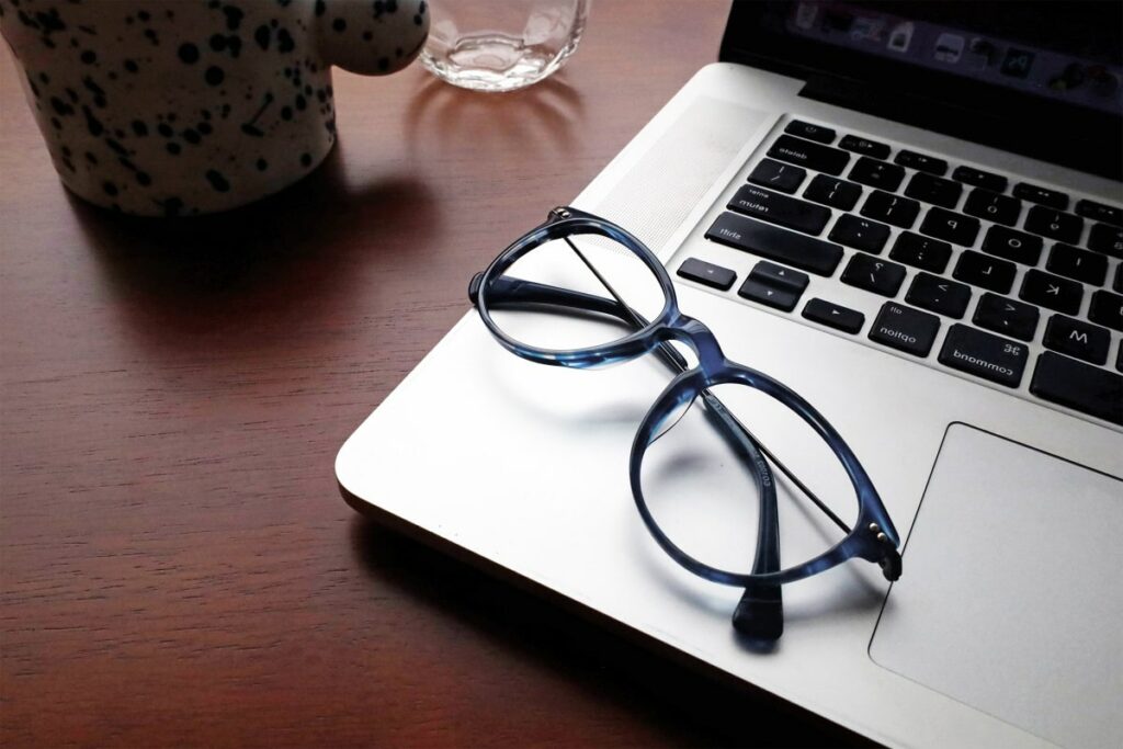 a pair of blue light glasses placed on a macbook