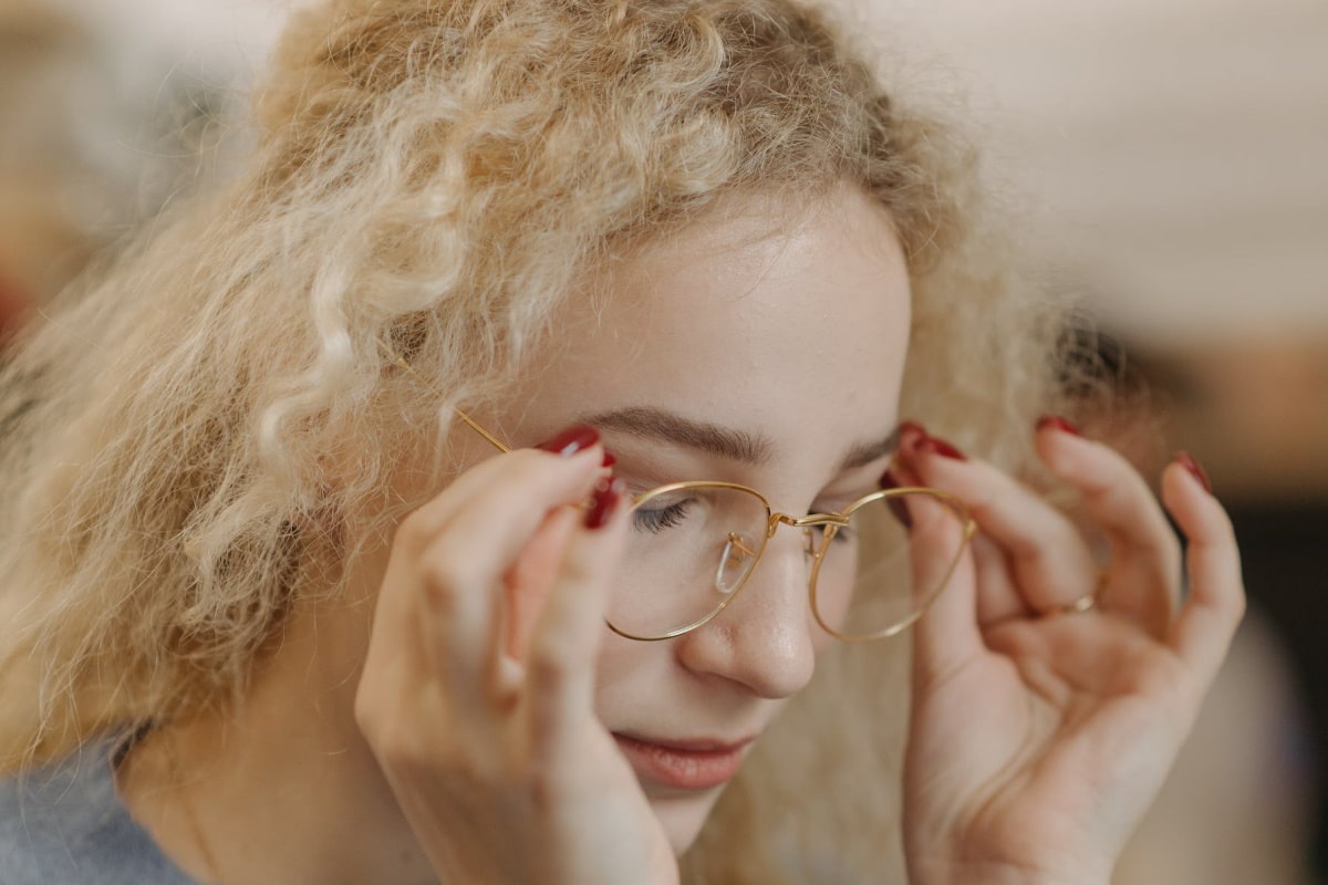 a woman removing eyeglasses from her face