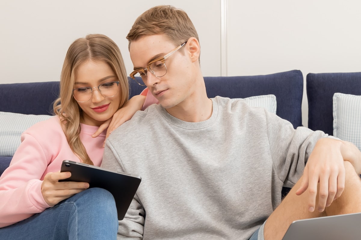 a couple wearing blue light glasses looking at a tablet