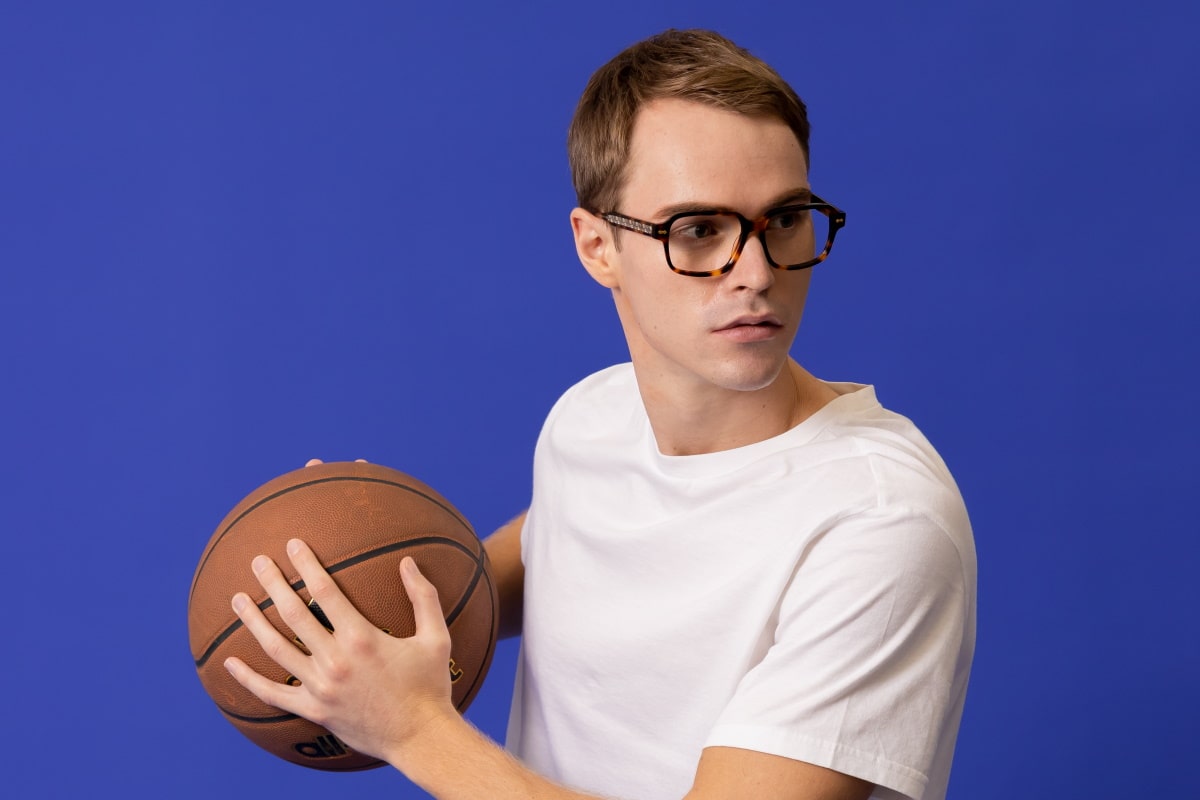 man wearing prescription glasses with trivex lenses while holding a basketball