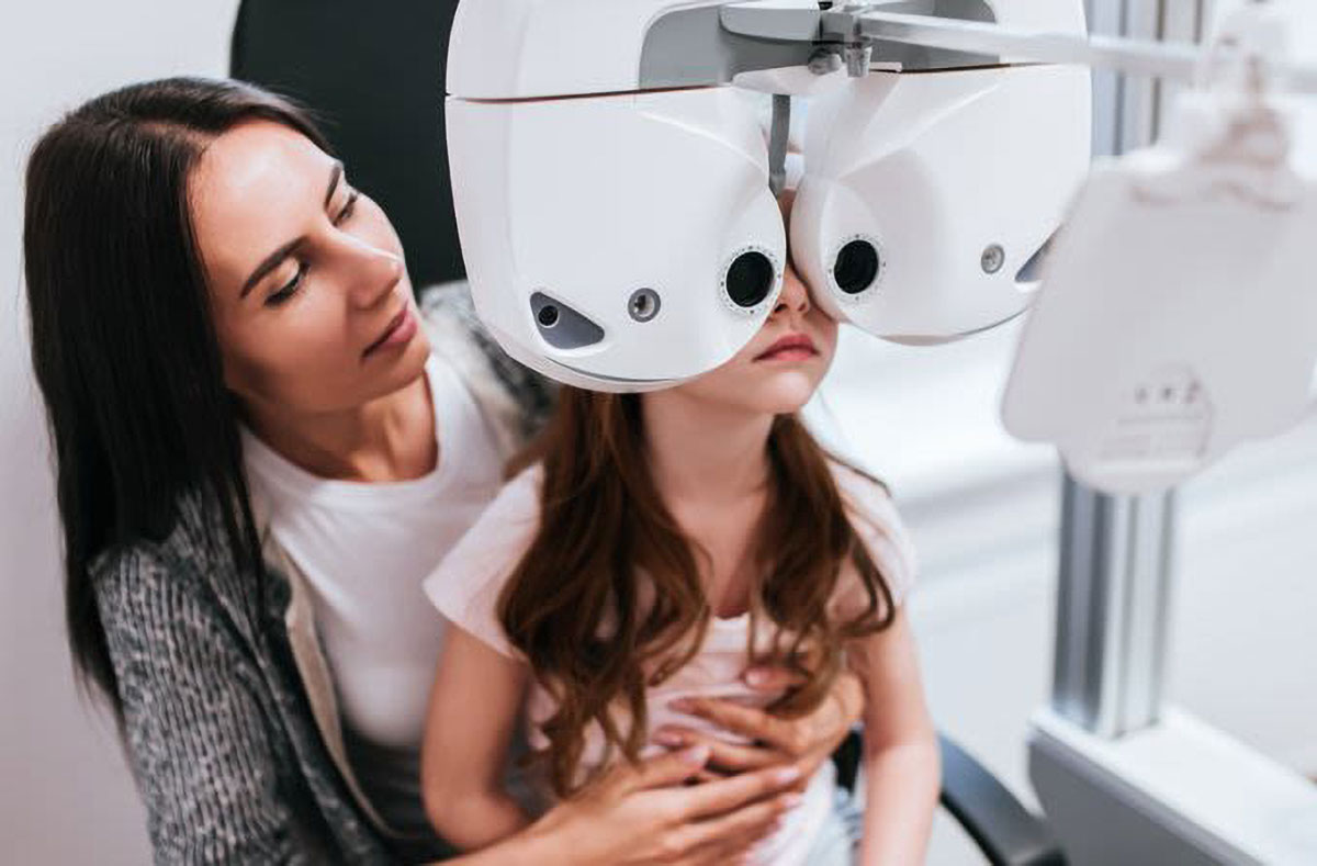 a mother helps her child being check for visual problems