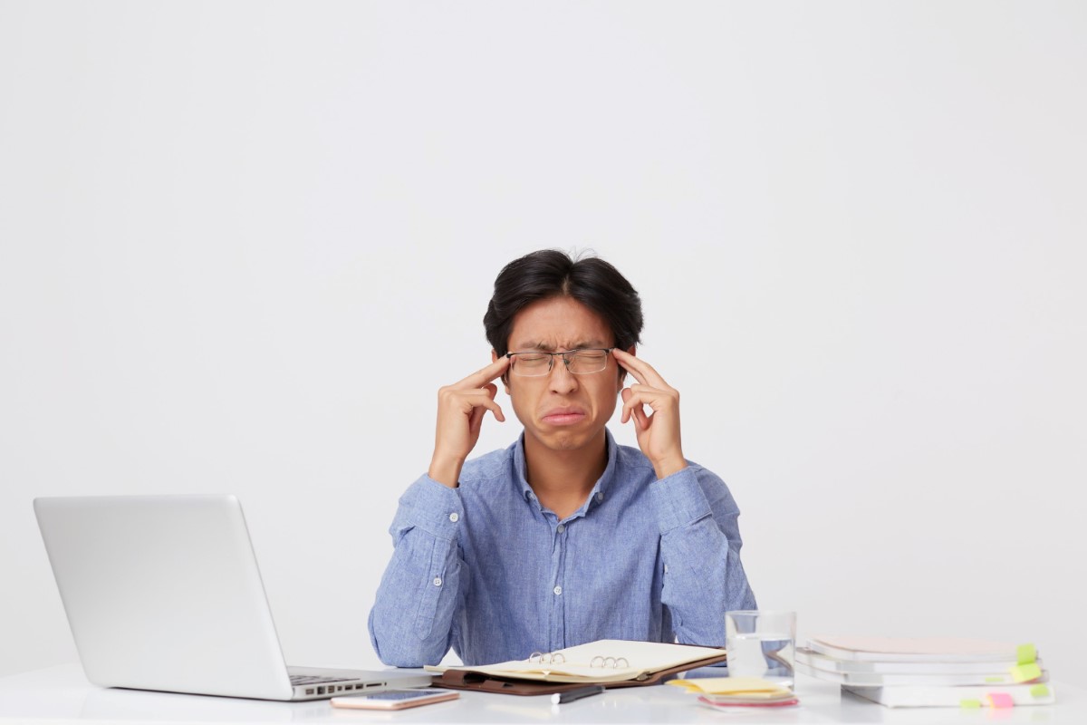 stressed asian young business man with glasses on having headache