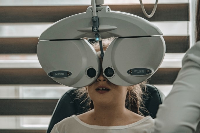girl using a phoropter in eye exam
