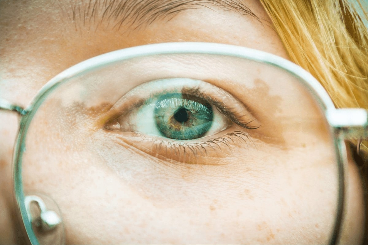 closeup of a green eye through eyeglasses lens