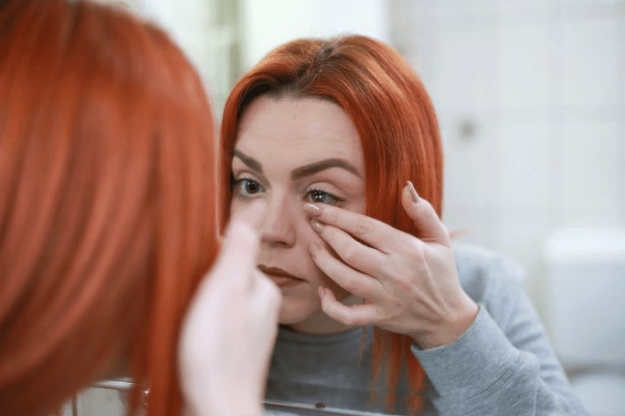 woman putting on contact lenses to aid her night blindness