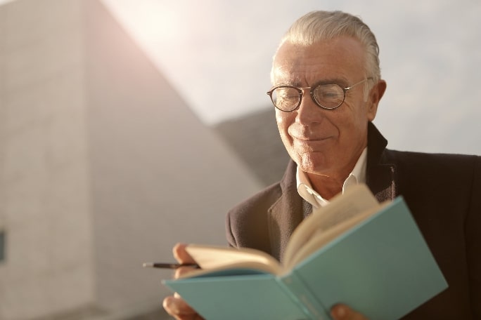 an old man wearing a pair of reading glasses while reading
