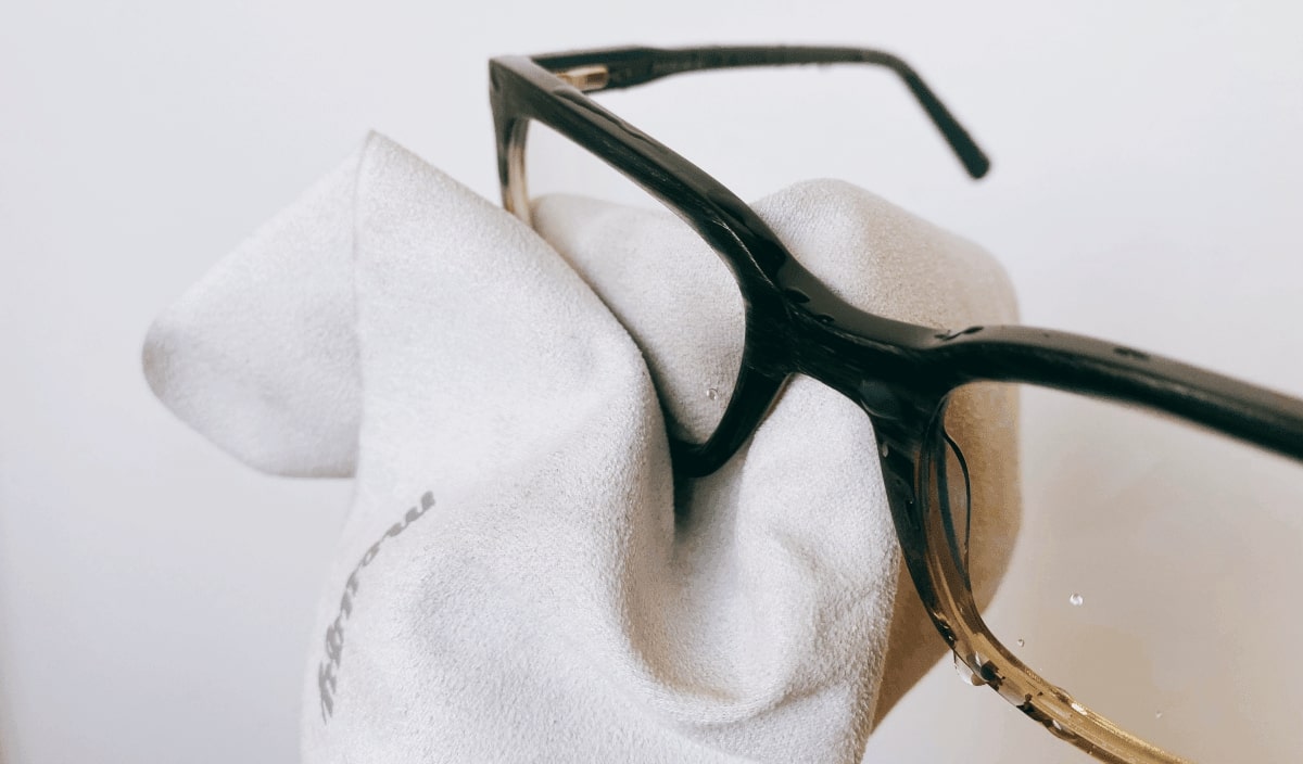 wiping a pair of glasses with microfiber cloth