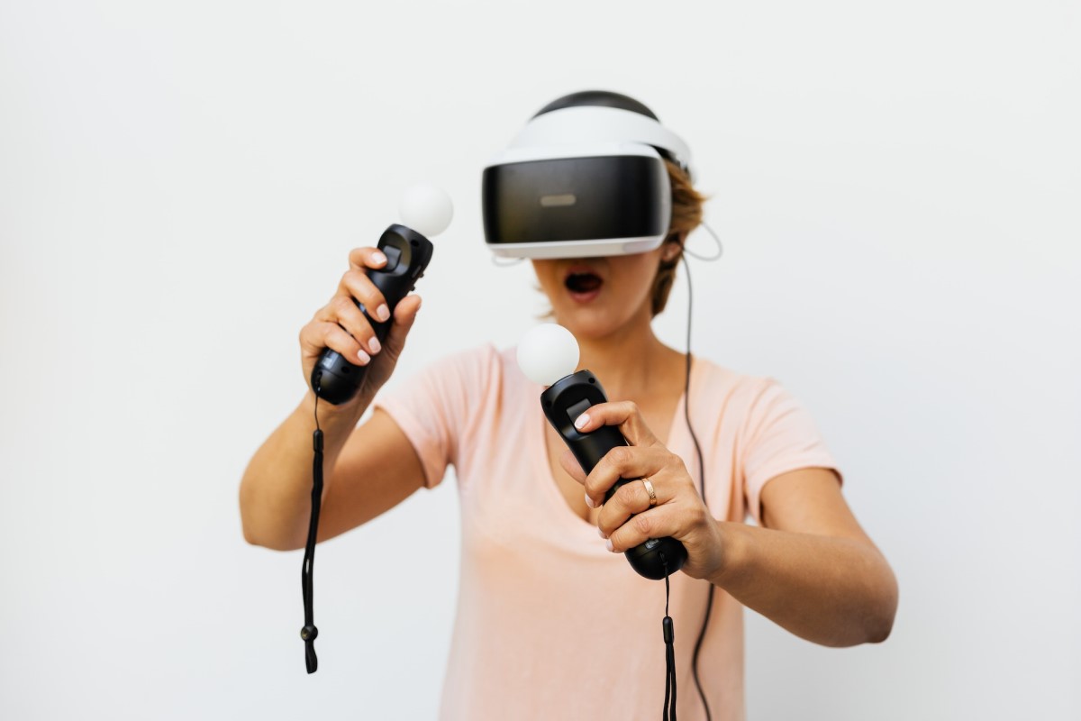 woman using a pair of VR headsets with handheld controls