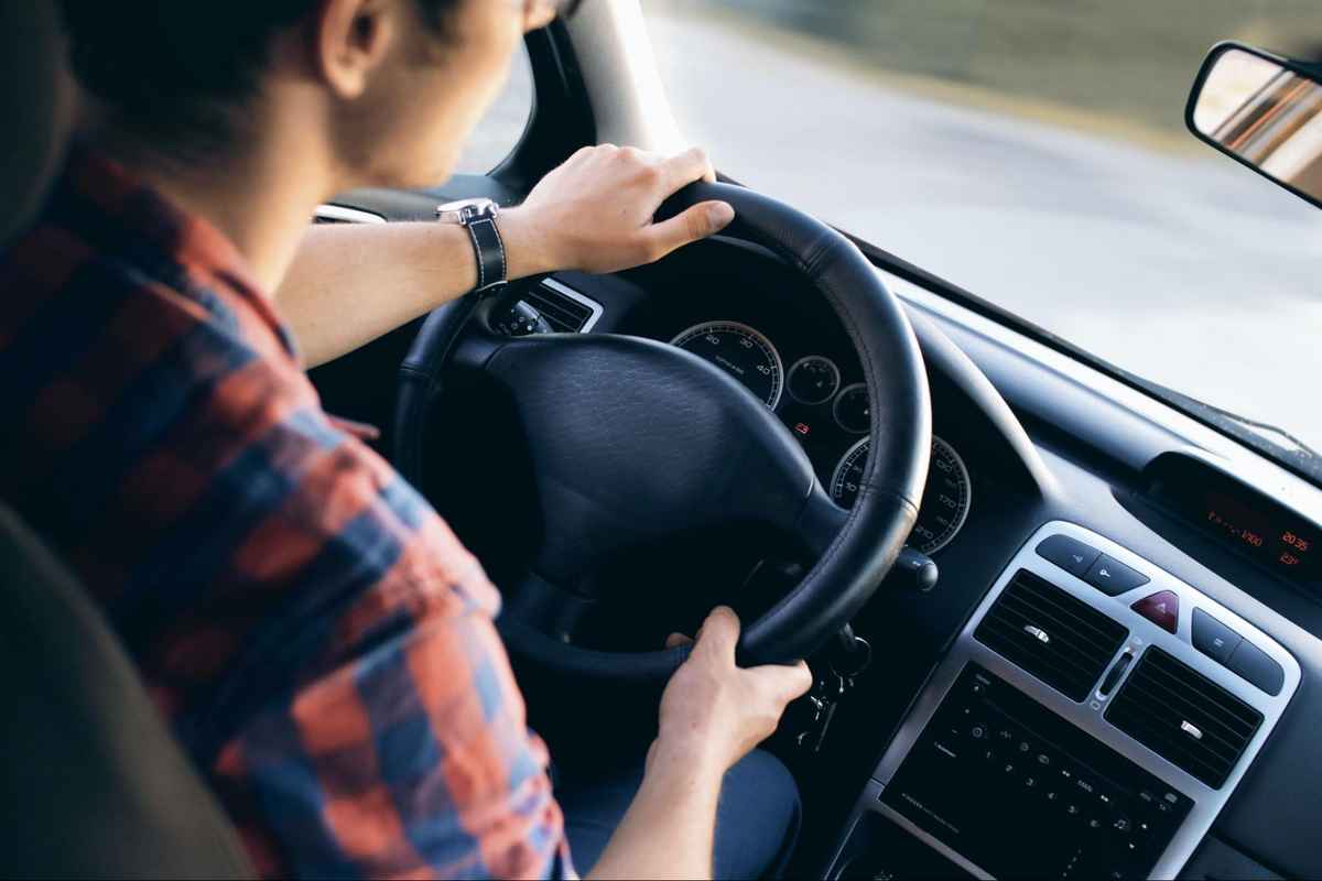 a man holding the steering wheel in a car with both hands