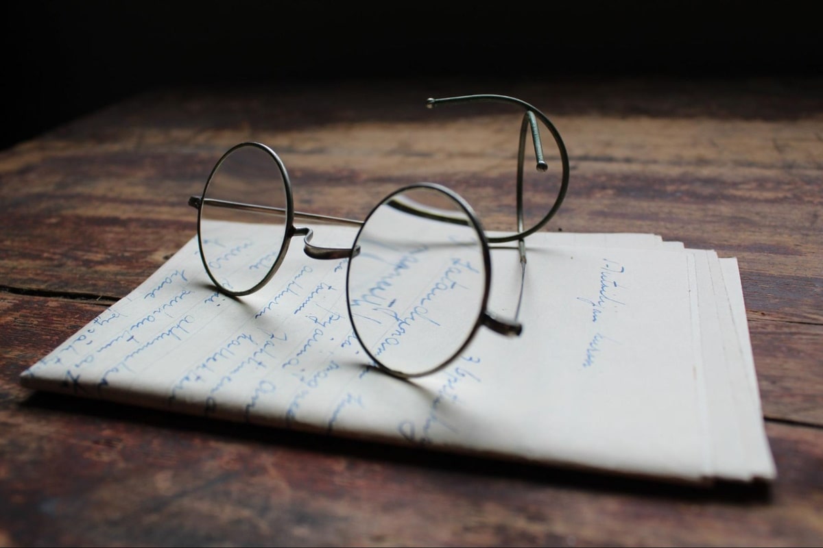 round glasses frame placed on top of a stack of papers