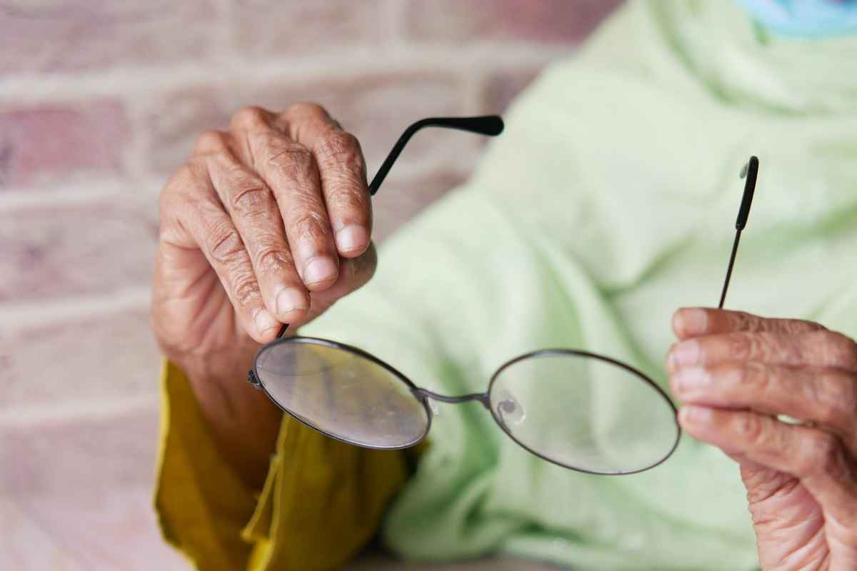 a person handling a pair of thin glasses frame with care
