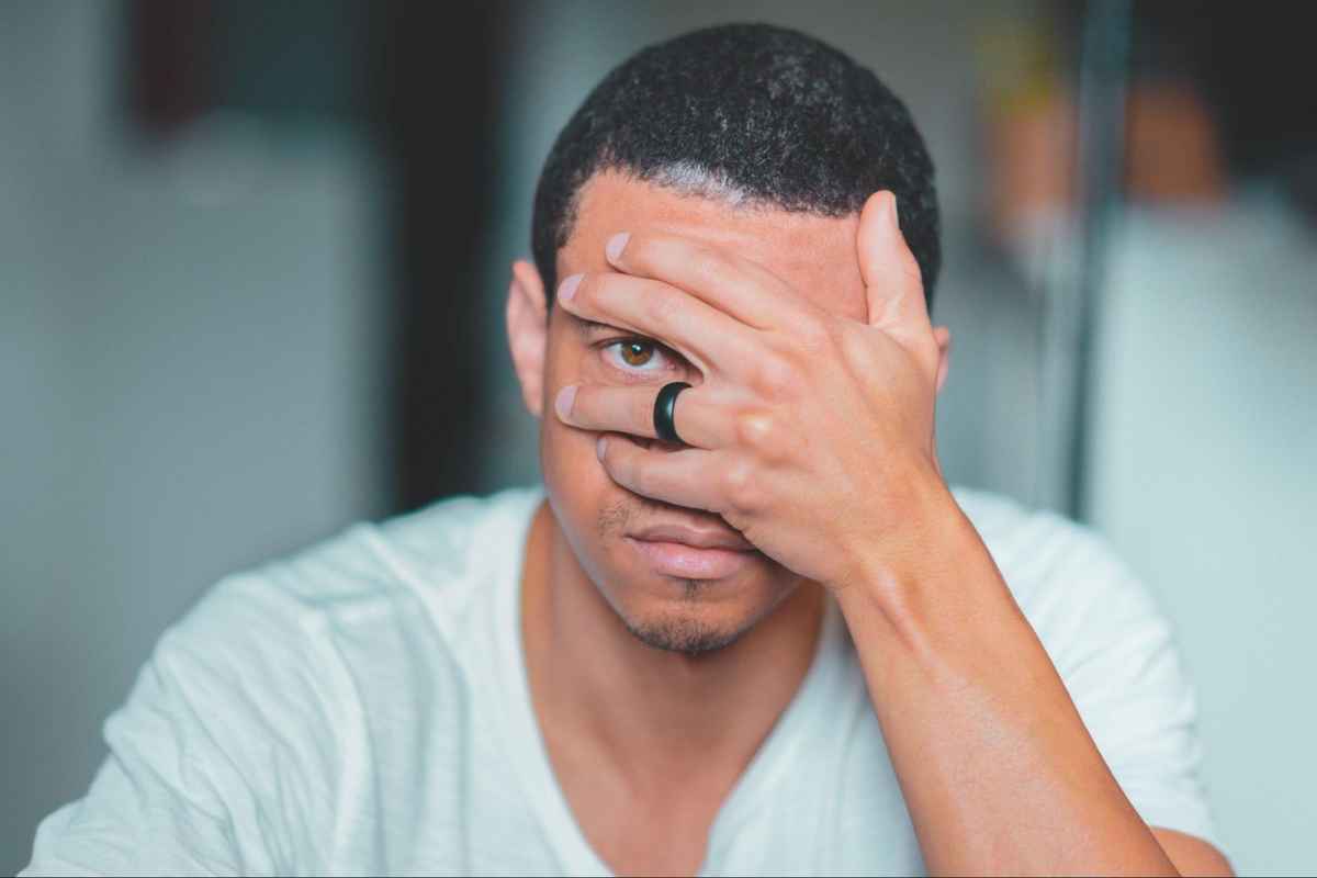 a man covering his left eye with his left hand
