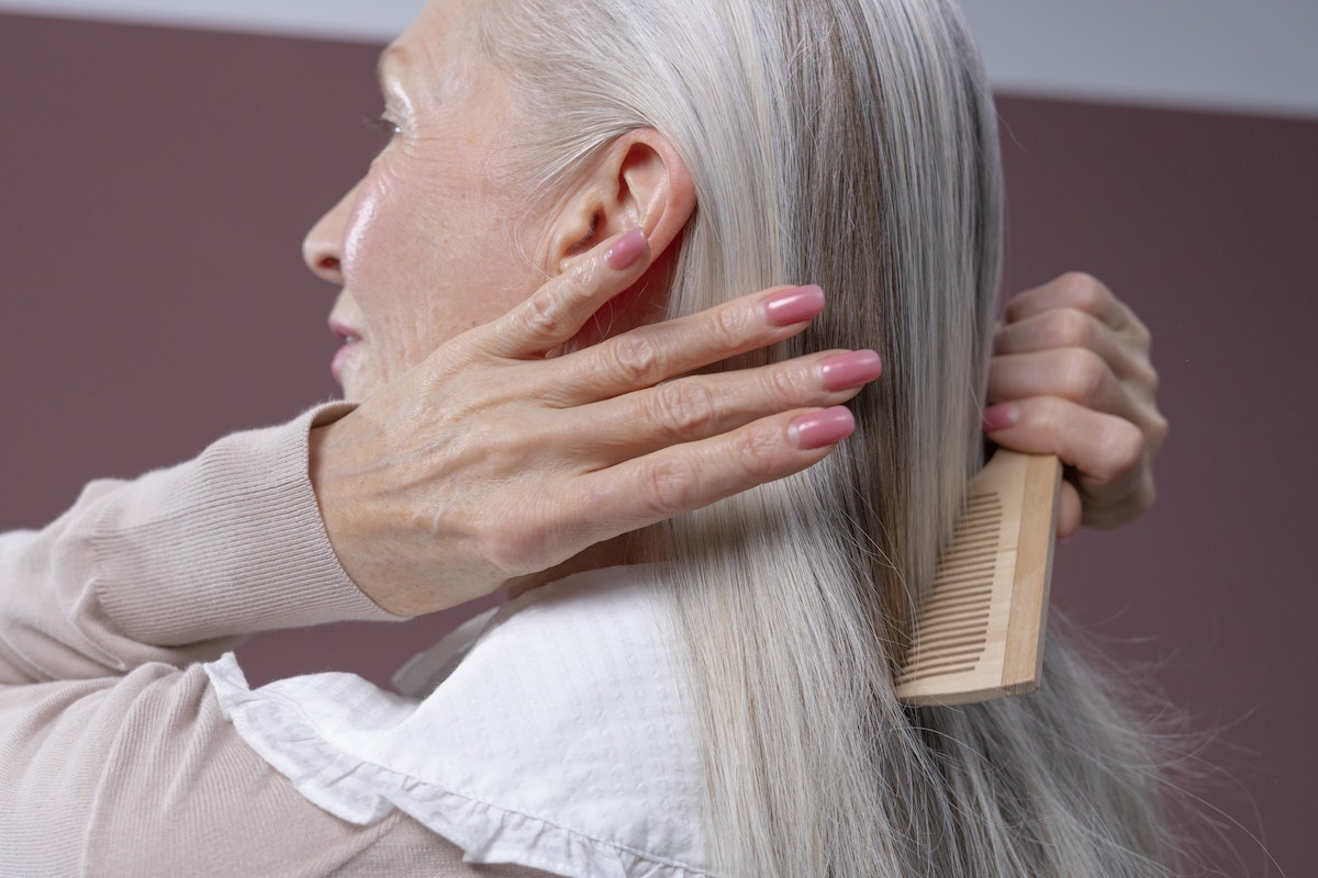 old woman combing gray hair