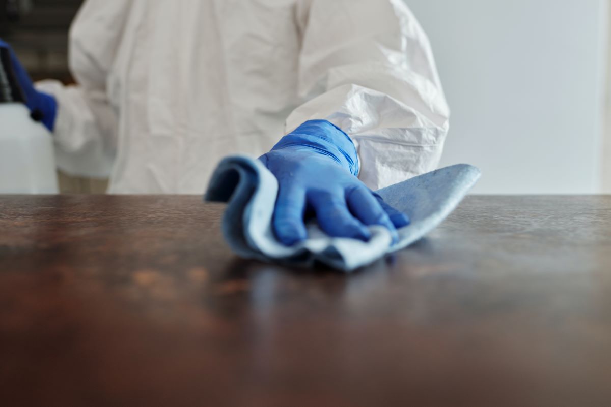 a person cleaning surfaces of a table to prevent petechiae