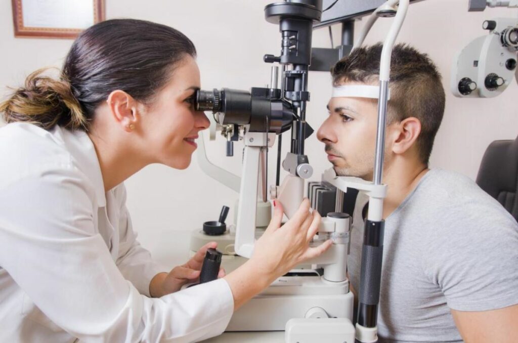 an eye doctor performing a slit eye exam on a male patient