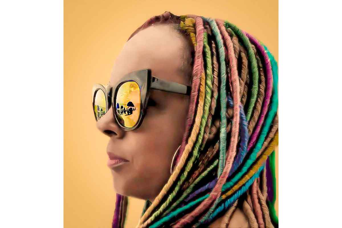 woman with rainbow braided hair wearing a pair of mirrored sunglasses