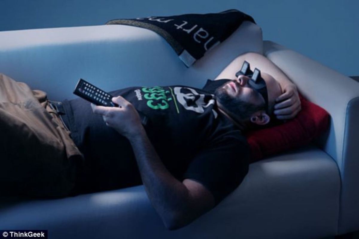man laying on a couch watching tv while wearing lazy glasses