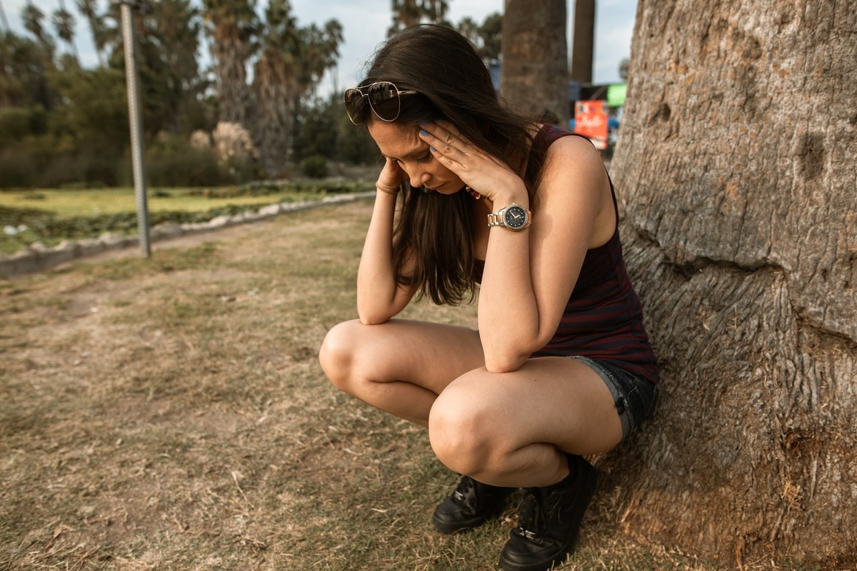 woman squatting by the tree experiencing anxiety