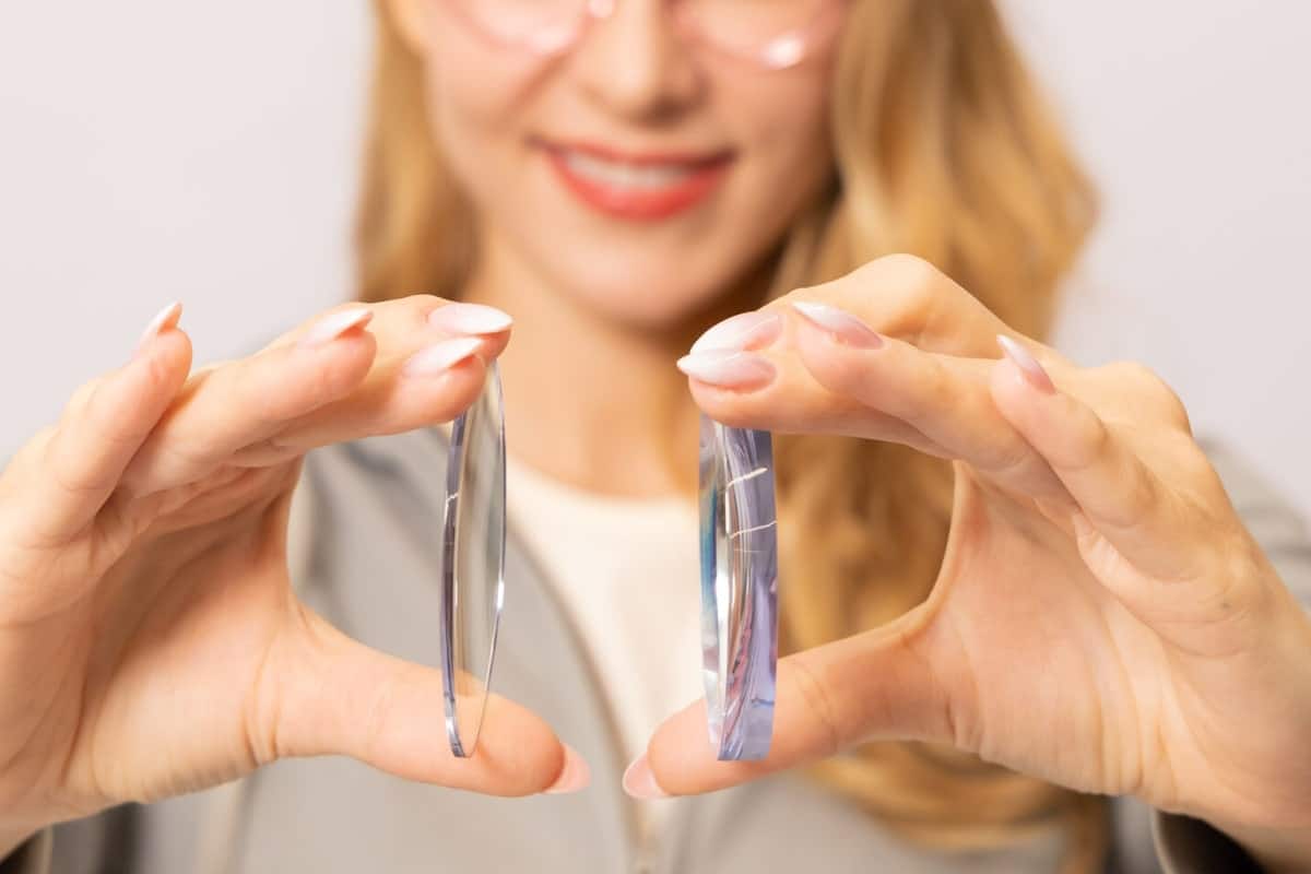 woman holding a piece of regular index lens and high index lens