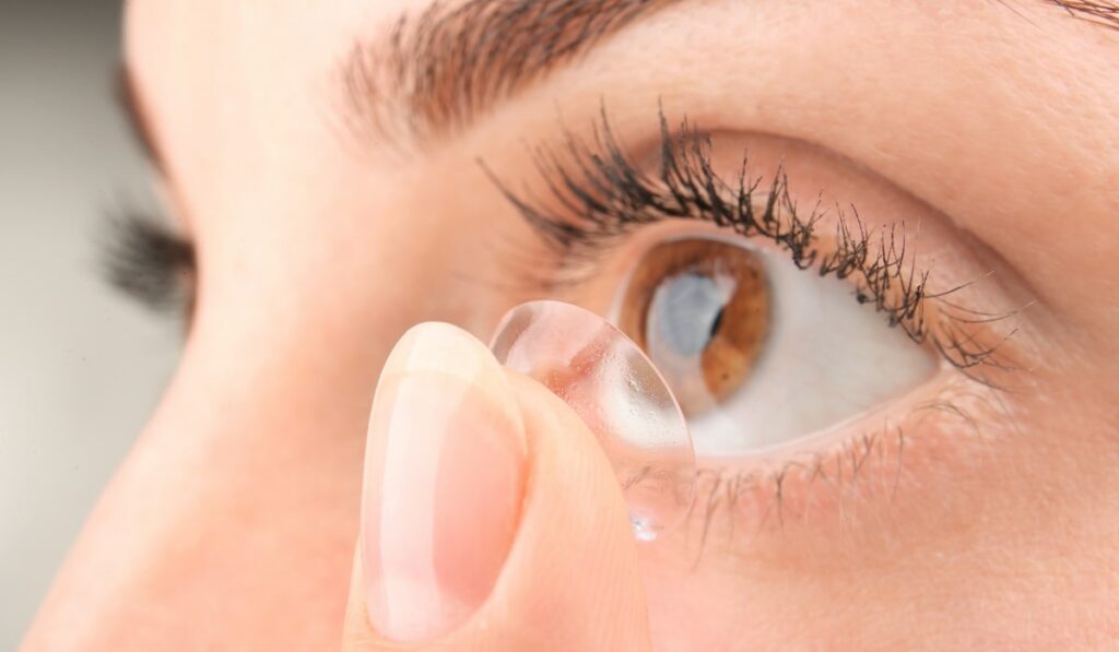 a closeup of a woman putting on contact lenses