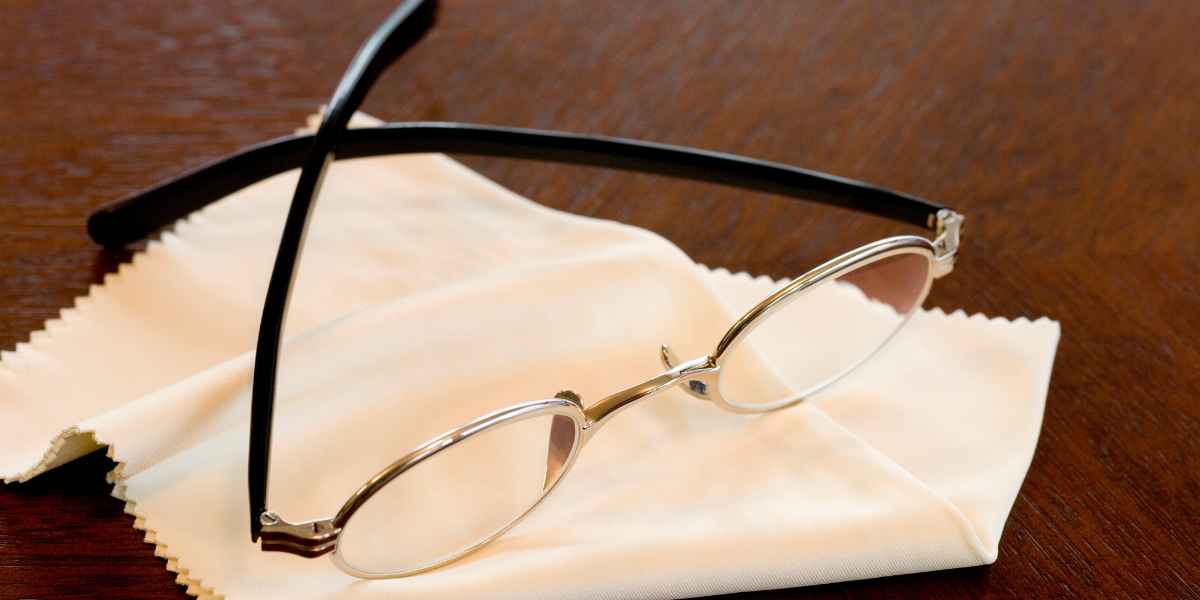 a pair of glasses placed on top of lens cloth