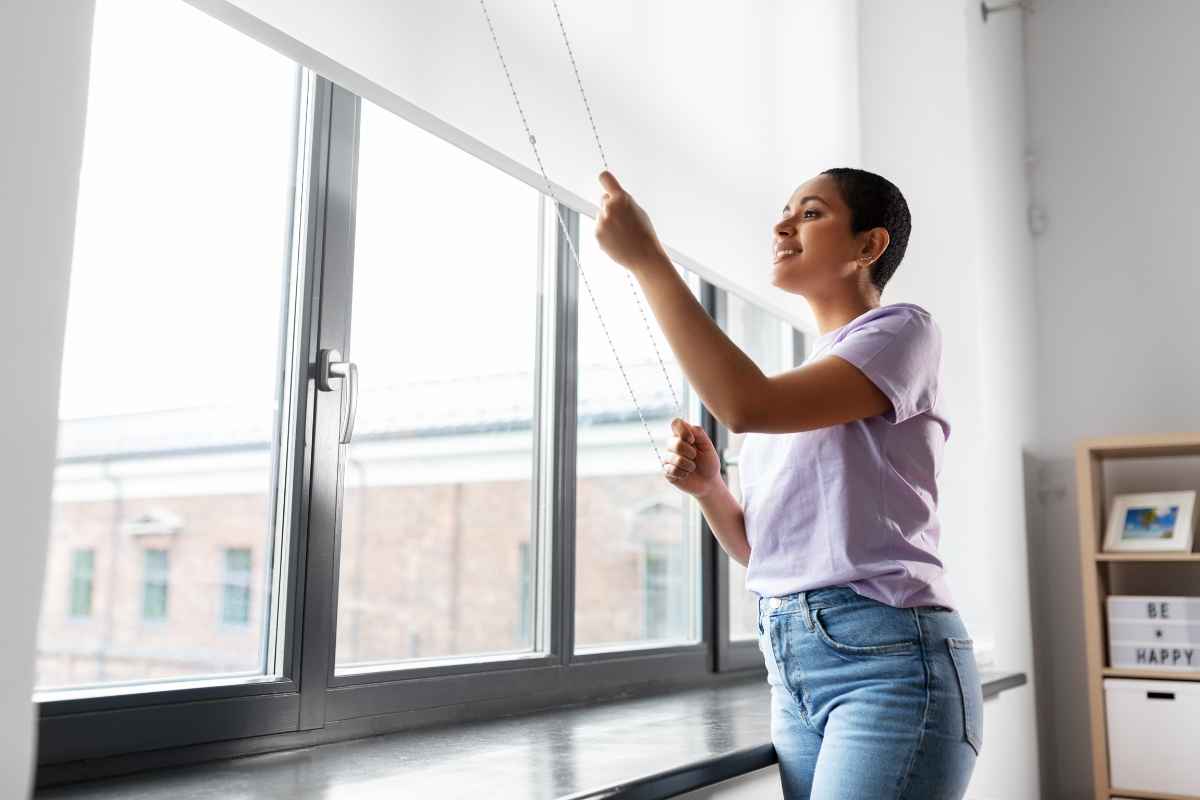 woman closing curtains to control brightness in the room