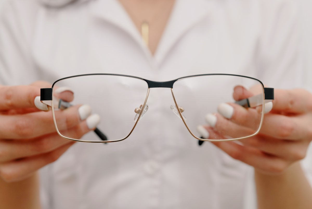 a person holding a pair of eyeglasses by the temple arms