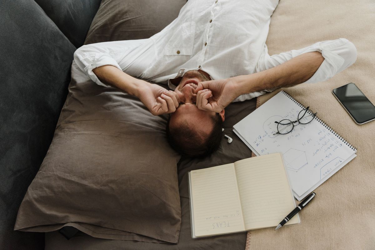 man rubbing eyes while lying down