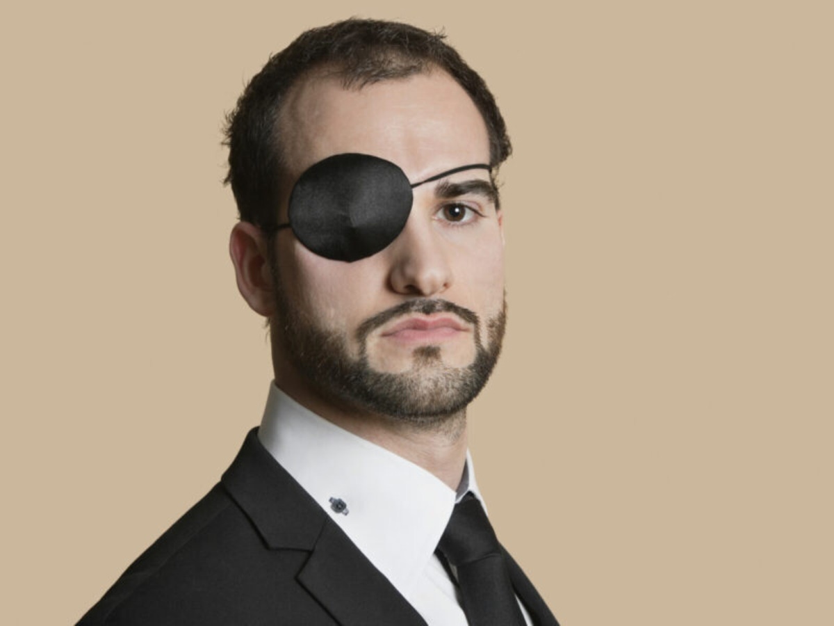 man in suit wearing a black eyepatch for cosmetic purposes