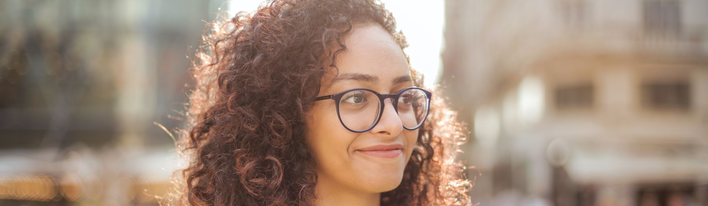 a woman with curly hair wearing a pair of blue oval glasses