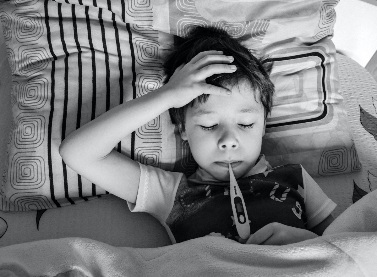 child with headache being checked for temperature