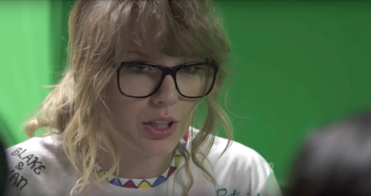 taylor swift with curly hair wearing a pair of black square glasses