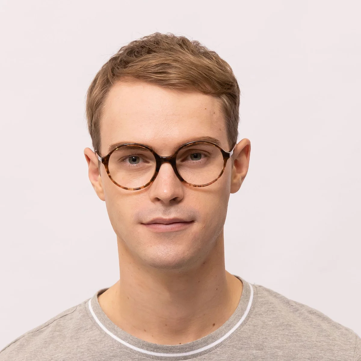 man wears round glasses that makes his eyes appear bigger