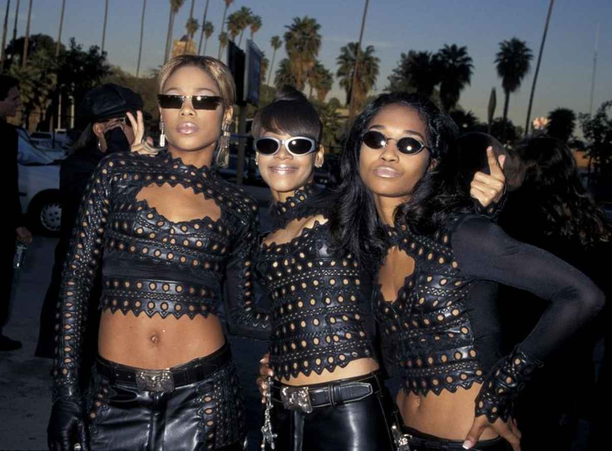 TLC wearing 90s oval sunglasses and coordinated leather ensembles