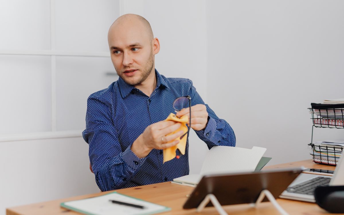 man cleaning his glasses with cloth cleaner