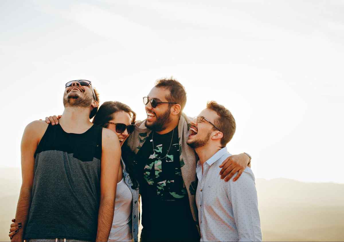 four people wear sunglasses while laughing