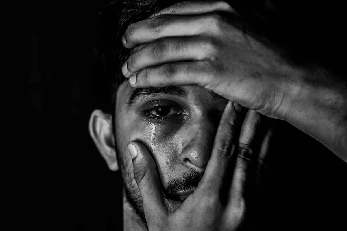 man experiencing eye socket pain while shedding tears