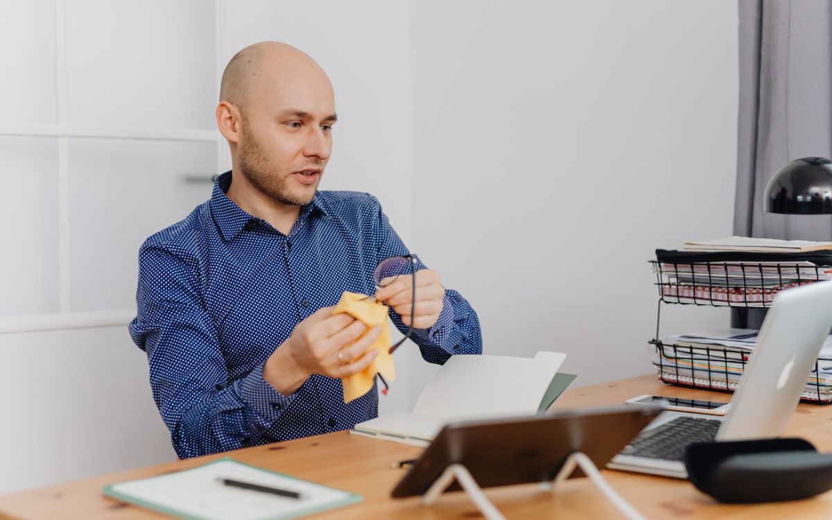 man cleaning his glasses with a cloth cleaner