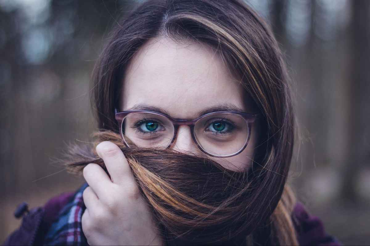 woman with glasses covers her face with hair
