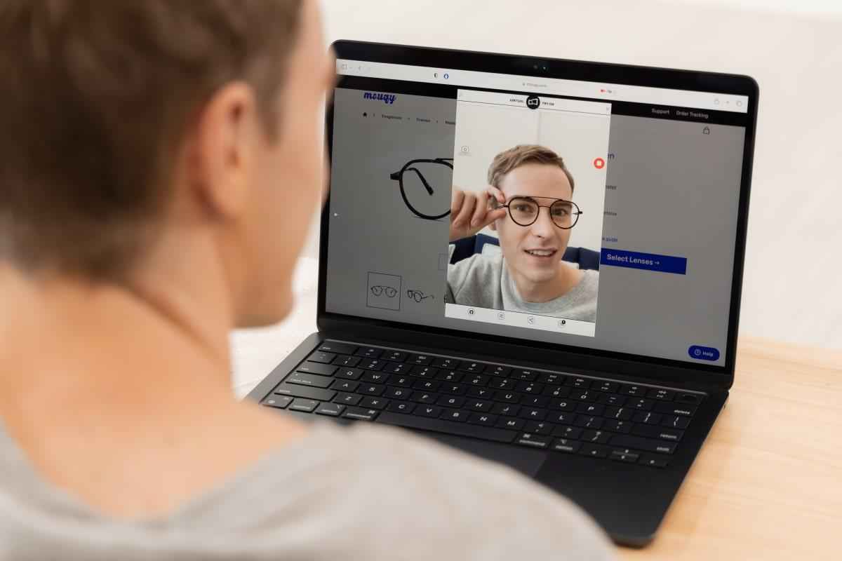 man try on glasses virtually with a laptop on mouqy website