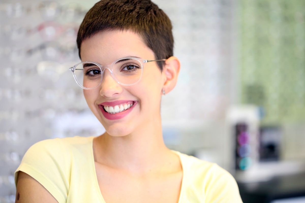 woman wears clear glasses in a yellow shirt