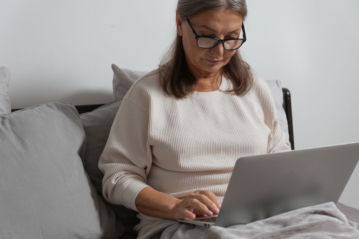 woman wears reading glasses while using her laptop
