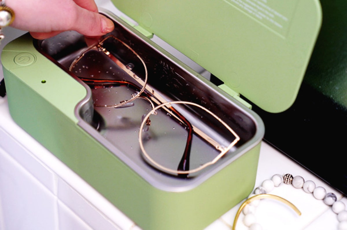 hand placing eyeglasses into an ultrasonic cleaning device