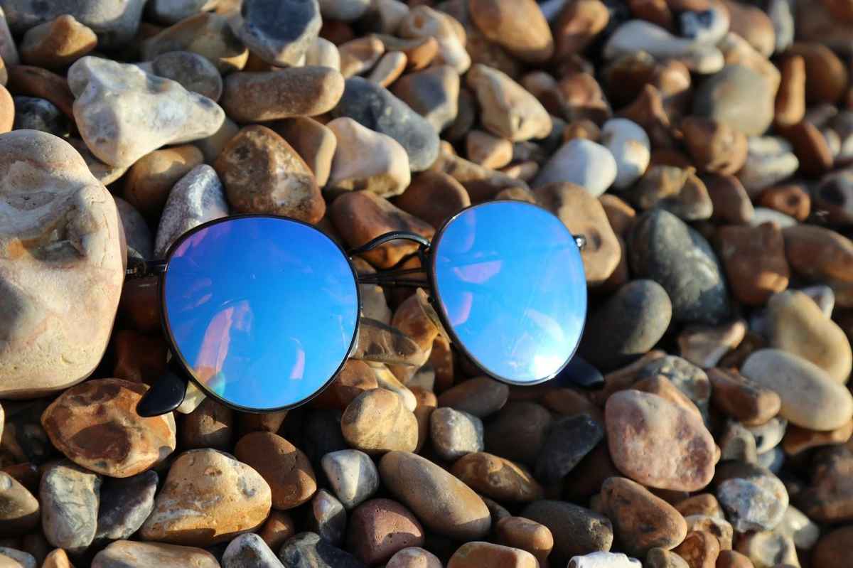 ray ban clubmaster sunglasses placed on top of pebbles