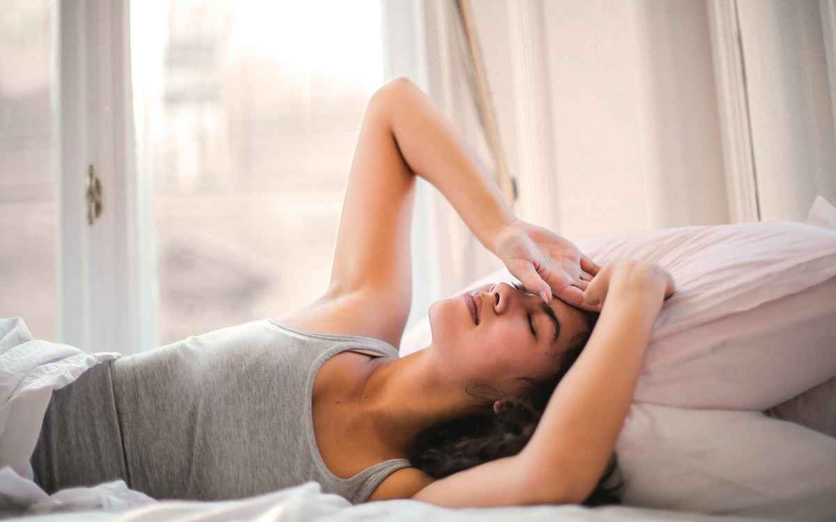 woman resting eyes on bed to alleviate eye socket pain
